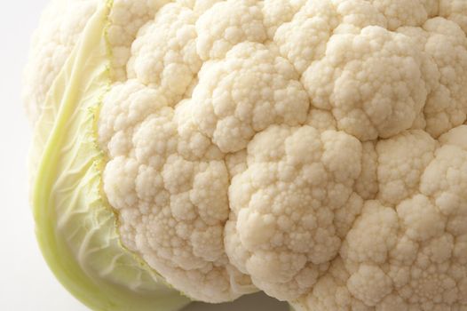 Close up view of the florets and texture of a head of fresh white cauliflower over a white background