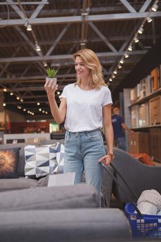 Vertical shot of a beautiful mature woman smiling, buying potted aloe plant at furnishings store