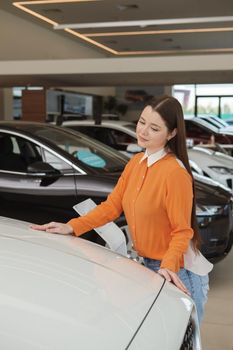 Vertical shot of a female customer choosing new car to buy at the dealership