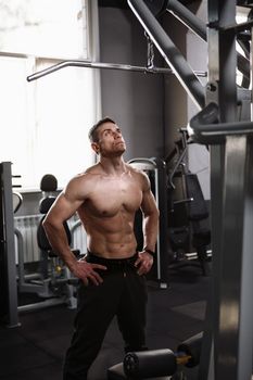 Vertical shot of a shirtless sportsman with ripped body standing in the gym