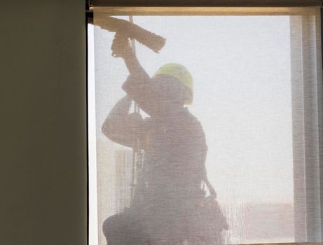 Silhouette of a rope access glass cleaner working at heights.