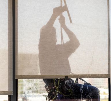 Silhouette of a rope access glass cleaner working at heights.