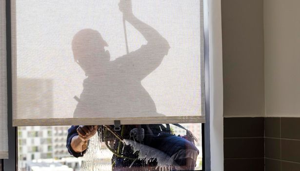 Silhouette of a rope access glass cleaner working at heights.