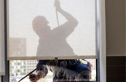 Silhouette of a rope access glass cleaner working at heights.