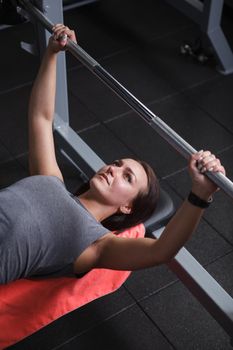 Vertical top view shot of a beautiful female athlete focusing before barbell bench press workout