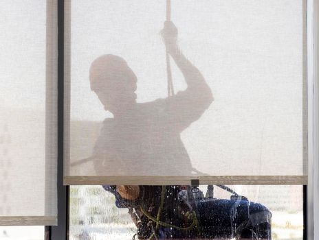 Silhouette of a rope access glass cleaner working at heights.