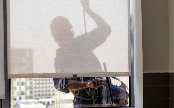 Silhouette of a rope access glass cleaner working at heights.