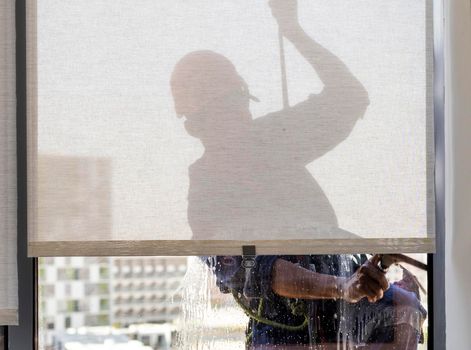 Silhouette of a rope access glass cleaner working at heights.