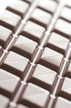 Selective focus angled view on delicious milk chocolate squares with little diagonal lines etched into them