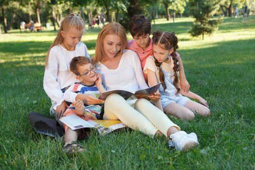 Group of little kids enjoying their lesson outdoors in the park with favorite teacher