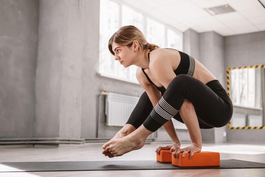 Young athletic woman balancing on her hands, practicing yoga, copy space