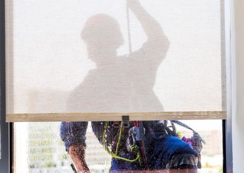 Silhouette of a rope access glass cleaner working at heights.