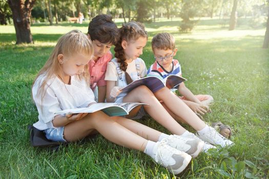 Schoolkids studying outdoors on the grass at ublic park
