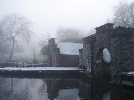 buildings on the side of a lake shrouded in fog