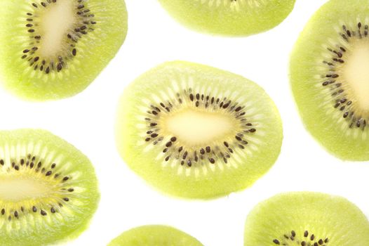 Thinly sliced and peeled exotic kiwifruit arranged on a white background for a decorative pattern showing the green flesh and ring of pips
