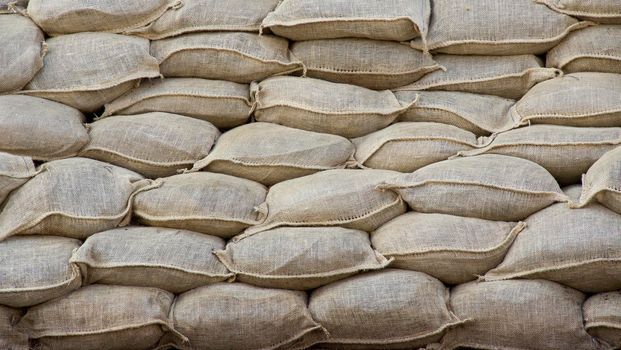 Background of lying dirty sandbags. Sandbag flood protection wall texture, texture. Bags to strengthen the defensive structure during the battle. Background
