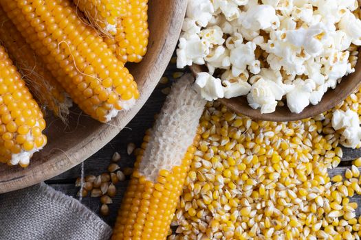 Harvesting popcorn from the cob flat lay with a bowl of popped corn surrounded by kernels and cob with kernels partially removed.