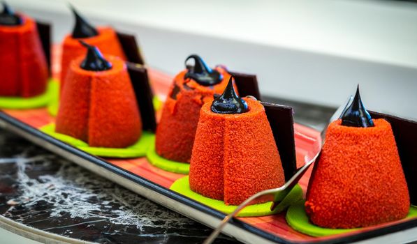 Small cone-shaped velveteen cakes decorated with chocolate paste.
