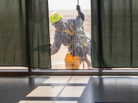 Silhouette of a rope access glass cleaner working at heights.