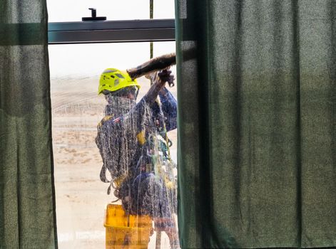 Silhouette of a rope access glass cleaner working at heights.