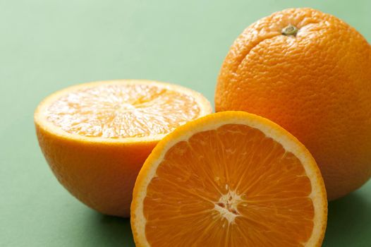 Close-up of one whole and cut orange on green background