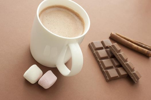 Hot chocolate drink with ingredients including marshmallows, stick cinnamon and a candy chocolate bar for a delicious winter beverage, high angle view