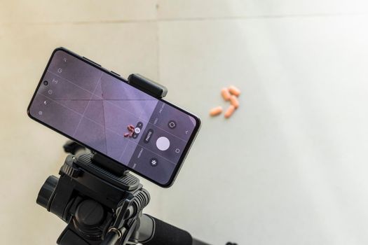 Close up shot of a phone on tripod capturing medicine on the surface