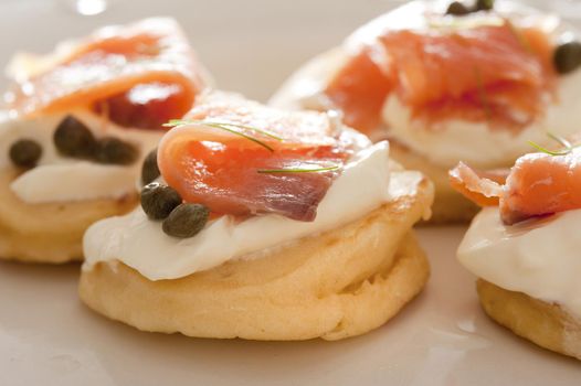 Close up of smoked salmon with capers and creme party food appetizers with strong light source from the top