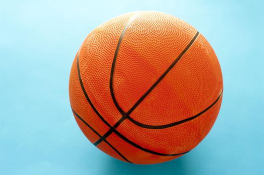 Close up of a single orange baseball on a colorful turquoise blue background with copyspace