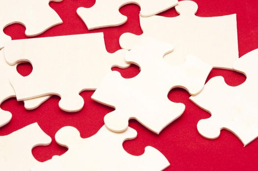 Scattered white jigsaw puzzle pieces on a colorful red background in a concept of problem solving