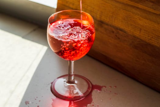 Shot of a red liquid being poured in to the wine glass.