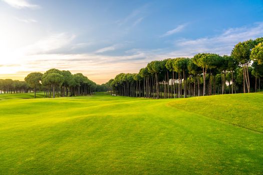 Golf course at sunset with beautiful sky. Scenic panoramic view of golf fairway