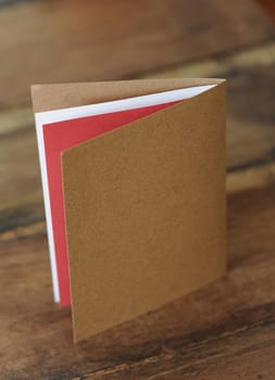 A blank greeting card in unbleached paper on a wooden surface
