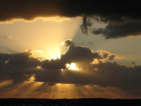 sunbeams shine out from a cloudy sky