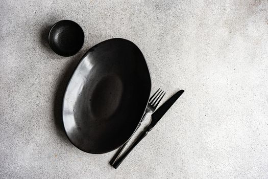 Minimalistic table setting with ceramic bowl and cutlery on concrete table