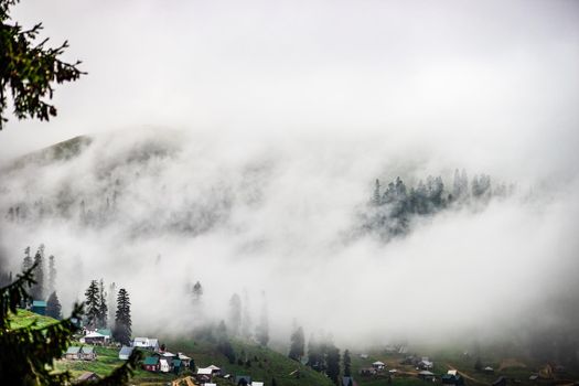 Traditional old wooden houses of Bakhmaro resort in georgian region Guria in foggy morning