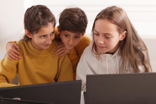 Group of kids chatting while working on a computer together