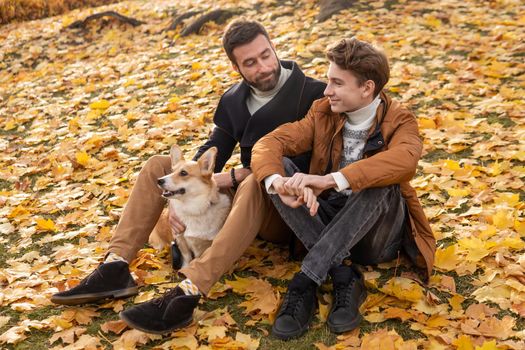 Father and son with a pet on a walk in the autumn park.