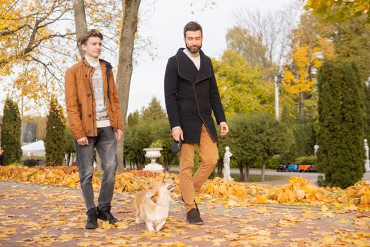 Father and son with a pet on a walk in the autumn park.