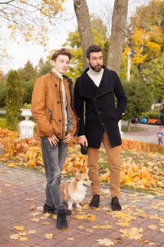 Father and son with a pet on a walk in the autumn park.