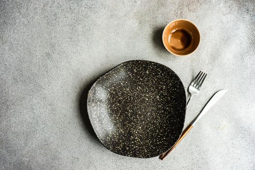 Minimalistic table setting with ceramic bowl and cutlery on concrete table