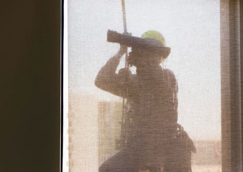 Silhouette of a rope access glass cleaner working at heights.