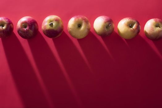 Fresh apples arranged in row on red background with copyspace