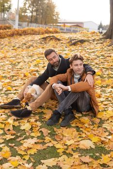 Father and son with a pet on a walk in the autumn park.