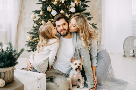 Happy family: mom, dad and pet. Family in a bright New Year's interior with a Christmas tree.