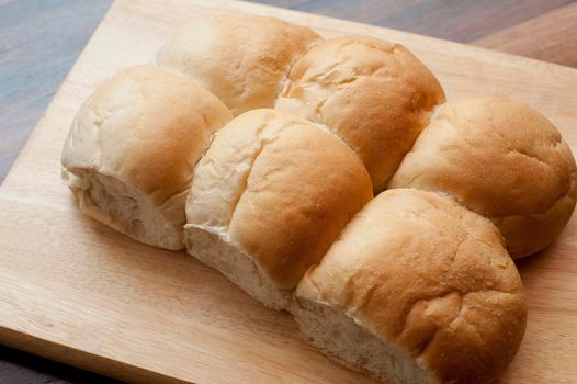 High angle view of a freshly baked batch of fresh round white cob rolls on a bread board