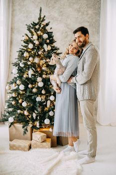 Happy family: mom, dad and pet. Family in a bright New Year's interior with a Christmas tree.