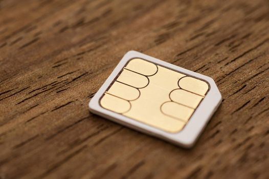 Micro-sim card for a mobile phone on a wooden background with shallow dof and partial focus in a communication concept