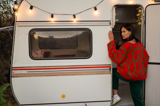 Caucasian woman in oversized red knitted jumper travels in motorhome in autumn