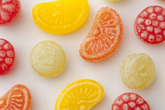Bright colorful fruity jelly candies in the shape of an orange, lemon, lime and berry arranged on a white background, overhead view